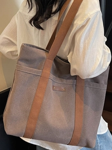 Spacious canvas tote bag in dark brown with front pocket and durable shoulder straps