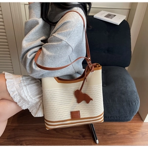 Close-up of knit tote bag featuring honeycomb texture and leather dog charm detail