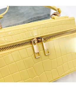 Close-up of bright yellow crocodile embossed leather handbag with dual gold zippers