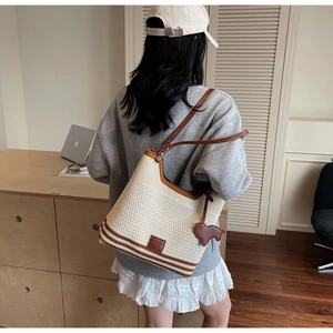 Detail of knitted tote bag with brown leather straps and animal charm in home setting