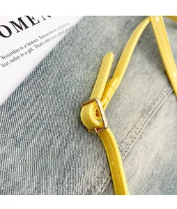 Detail of adjustable glossy yellow leather strap with high-quality golden metal buckle