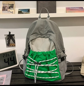 Detail of waterproof nylon backpack with green pocket and elastic cords for outdoor sports