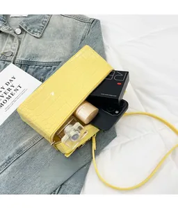 Detail view of bright yellow croc-pattern box bag showing spacious interior with cosmetics