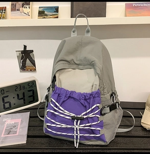 Detail of grey and purple outdoor backpack showing bungee cords and side mesh pocket