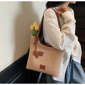 Detail of the beige knitted tote bag featuring a leather lamb charm and floral tulip decor