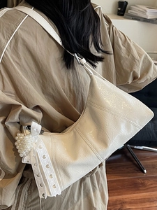 Chic cream pleated leather underarm bag with pearl heart charm and lace strap on a model