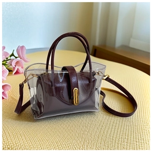 Detail view of transparent PVC tote bag with burgundy inner pouch and gold buckle