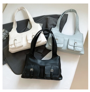 Detailed view of three minimalist underarm bags in white, light blue, and black faux leather