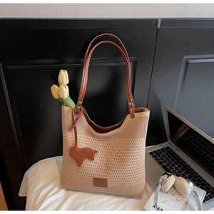 Detail of knit tote bag with brown leather pig charm and reinforced metal rivets