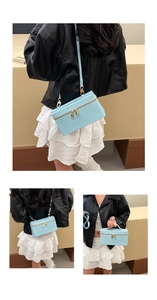 Detail view of sky blue crocodile pattern box bag with golden zippers and detachable strap