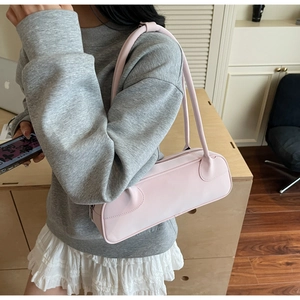Detail view of a pale pink Boston bag worn as a shoulder bag with soft leather texture