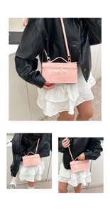Detail of pink croc-embossed box bag featuring golden zippers and a detachable strap
