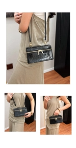 Detail of black crocodile-embossed leather mini bag with golden double zipper closure