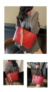 Detail view of red glossy tote bag with silver chain strap and fashion logo print