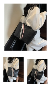 Detail of black tote bag with chain strap and stylish woven rope pendant accessory