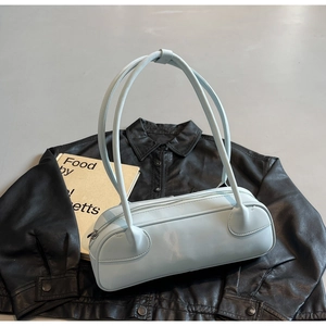 Top view of a light blue Boston bag on black leather jacket with a yellow book
