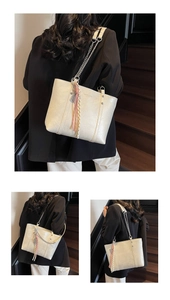 Detail of minimalist cream tote bag showing chain strap and tassel on a staircase