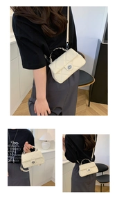 Dettaglio della borsa a tracolla trapuntata beige con catena in metallo e chiusura a vite
