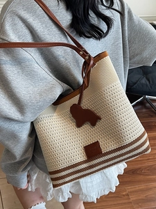 Knitted tote bag in cream white with brown stripes and leather dog charm on casual model
