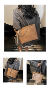 Detail view of large brown leather tote bag with chain strap and tassel charm detail