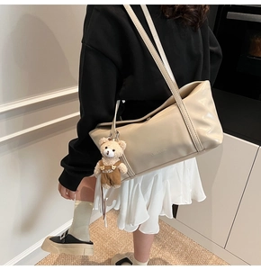 Dettaglio della borsa a tracolla beige in ecopelle con un simpatico ciondolo a forma di orso