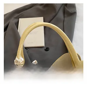 Détail du sac jaune clair à texture crocodile avec foulard et zip doré brillant