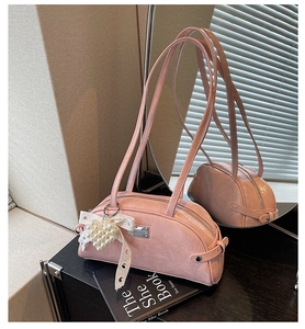 Détail du sac rose avec nœud en dentelle, pendentif cœur perlé et plaque métallique