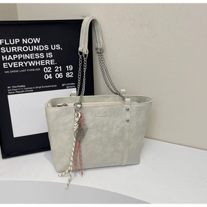 Detail of light gray leather tote with silver chain and woven rope decorative keychain
