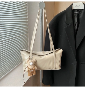 Dettaglio della borsa tote in pelle bianco crema con ciondolo a orsetto di peluche e logo