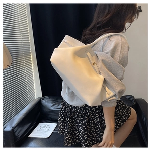 Detail of white soft leather tote bag with unique strap design and pleated texture