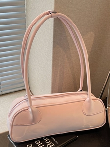 Pink Boston handbag with long straps and silver zipper on a stack of books