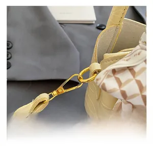 Détail d'un sac à main jaune à motif crocodile avec crochet doré et foulard en soie décoré