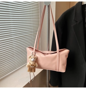 Dettaglio borsa a tracolla rosa in PU con logo inciso e ciondolo a forma di orsetto