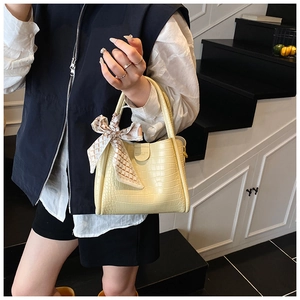 Détail du sac seau jaune clair avec texture crocodile et foulard en soie décoratif chic