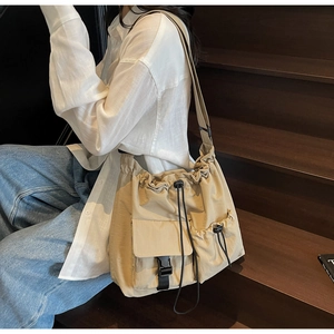 Detail of beige nylon tote bag with drawstring closure and buckle front pocket