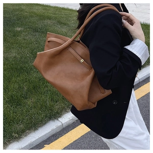 Outdoor shot of a caramel leather tote bag detail with side strap and metallic buckle