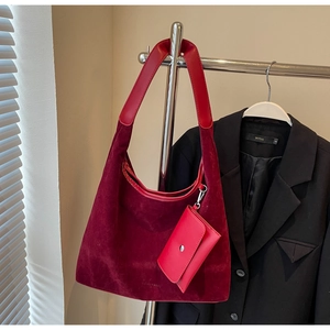 Large dark red suede tote bag with matching strap and coin purse hanging on a stand