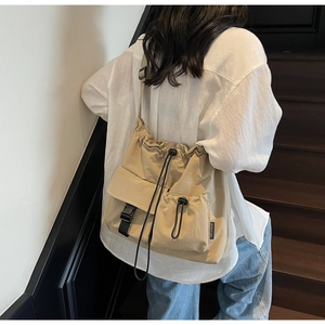 Detail of khaki nylon tote bag with drawstring closure and buckle pocket on model