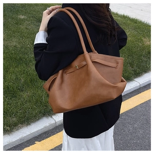 Brown leather tote bag styled with black blazer for an elegant commuter aesthetic