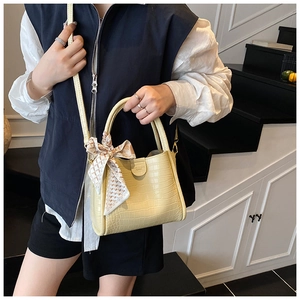 Détail du sac à main jaune clair à motif crocodile avec foulard en soie et fermoir en métal