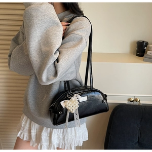 Détail du sac à bandoulière noir brillant avec pendentif nœud perlé et fines lanières