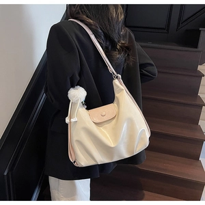 Detail of minimalist cream and pink tote bag with fuzzy charm on model in dark setting