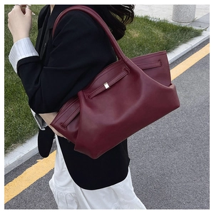 Detailed close-up of dark red leather tote bag with side belt straps and metal buckle