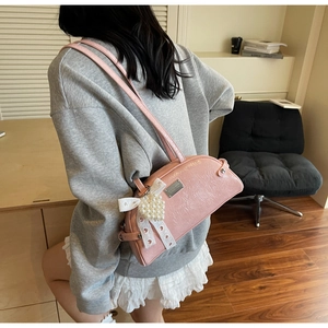Détail du sac rose avec nœud en dentelle, breloque cœur perle et cuir brillant texturé