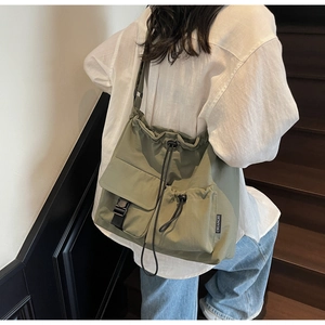 Detail of olive green nylon crossbody bag with drawstring closure and buckle pocket