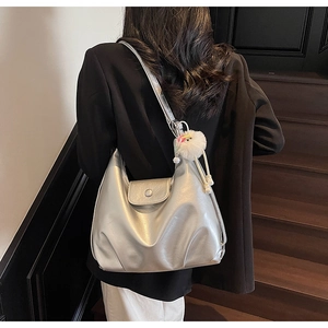 Detail of silver metallic hobo bag with white fuzzy charm and magnetic closure flap