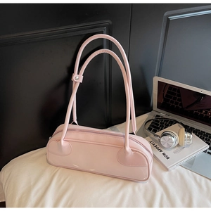 Vue détaillée du sac baguette rose rectangulaire avec anses fines sur surface en tissu