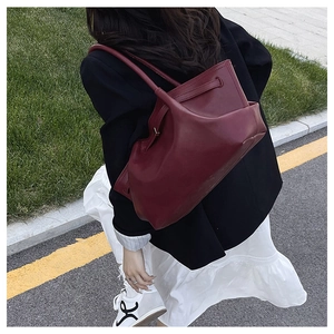 Detail of burgundy tote bag with drawstring texture shown on model in street setting