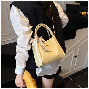 Détail du sac seau crème à motif crocodile avec foulard en soie sur l'anse et bandoulière