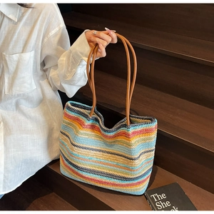 Close-up of colorful striped woven tote bag with brown leather handles on wooden steps